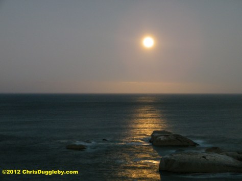 The sea and rocks illuminated by the setting of the full moon